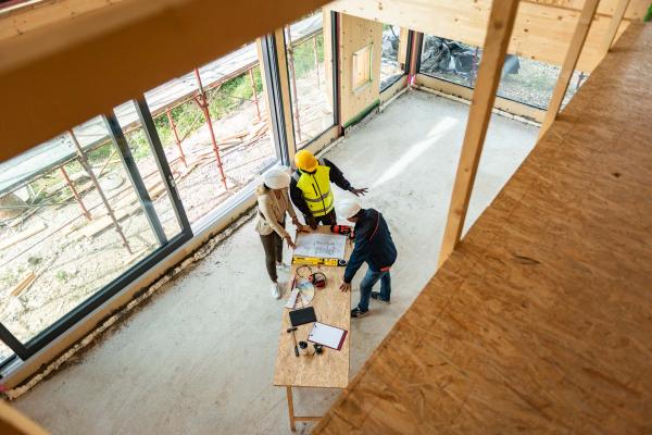 Team of one female architect and two male construction workers on a commercial construction site.