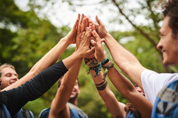 Shot of a team high fiving while on a team building day in a forest