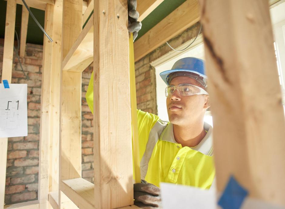 Carpenter measuring stud work on building