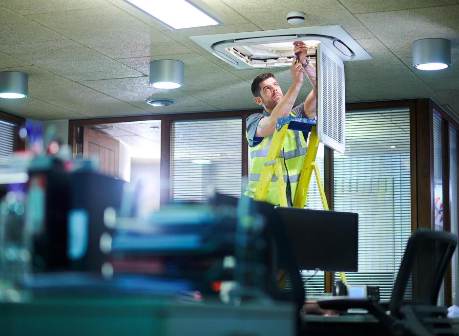 Engineer installing new air conditioning unit in an office